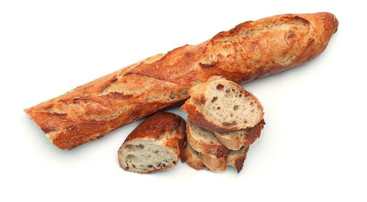 Ein ganzes Baguette und mehrere Baguettescheiben sind auf einem weißen Hintergrund angeordnet. Das Brot hat eine goldbraune, knusprige Kruste und ein weiches, luftiges Inneres.