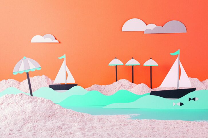 Papierausschnitt-Szene von Segelbooten auf dem Wasser mit Sonnenschirmen und Wolken vor einem orangefarbenen Hintergrund. Das Design verwendet Pastellfarben und strukturiertes Papier, um eine verspielte, sommerliche Strandatmosphäre zu schaffen.