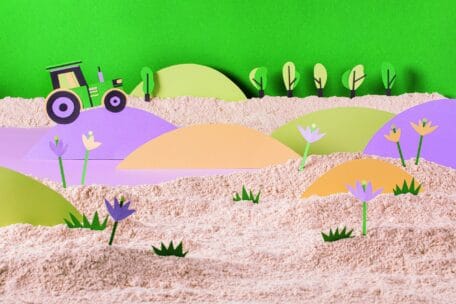 Eine farbenfrohe Landschaft im Scherenschnitt-Stil mit einem grünen Traktor, sanften Hügeln, verstreuten Bäumen und Blumen, die in sandigem Gelände vor einem strahlend grünen Himmel wachsen.