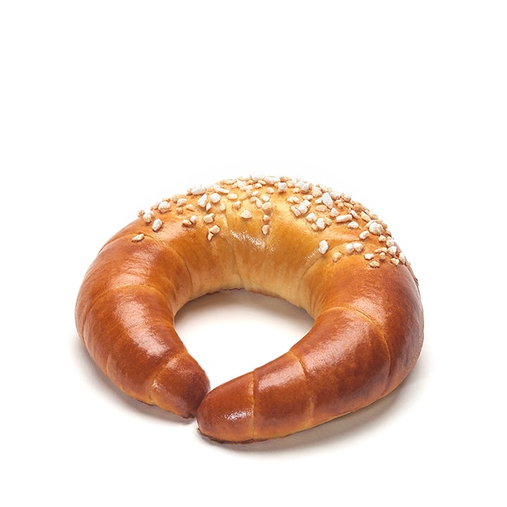 Ein halbmondförmiges Gebäck mit goldbrauner Kruste, das mit groben Zuckerkörnern bestreut ist und auf einem schlichten weißen Untergrund liegt.