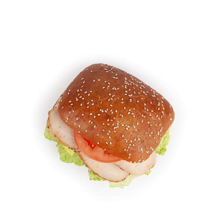 Ein Sandwich mit einem quadratischen Sesambrötchen, Schichten von geschnittenem Truthahn, Salat und Tomate, von oben gesehen auf einem weißen Hintergrund.