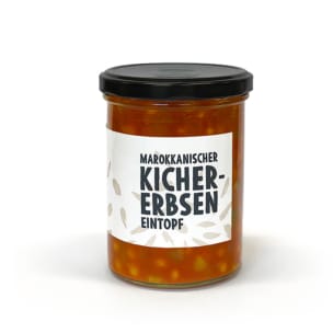 Ein Glasgefäß mit schwarzem Deckel, das einen marokkanischen Kichererbseneintopf enthält. Auf dem weißen Etikett steht in fetten Buchstaben "Marokkanischer Kichererbsen Eintopf", um den Text herum sind kleine Abbildungen von Kichererbsen zu sehen.