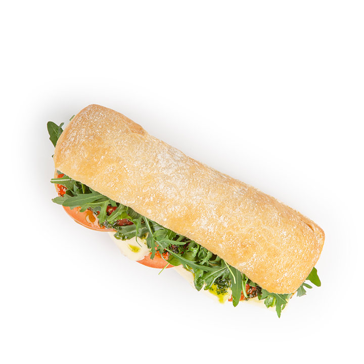 Ein Ciabatta-Sandwich, gefüllt mit frischem Rucola, geschnittenen Tomaten, Mozzarella und Pesto, fotografiert auf weißem Hintergrund.