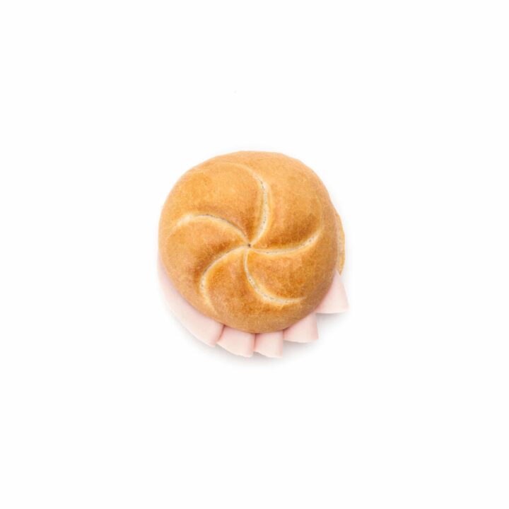 Ein rundes Sandwichbrötchen mit gewellter Oberseite, gefüllt mit Wurstscheiben, dargestellt vor einem schlichten weißen Hintergrund.