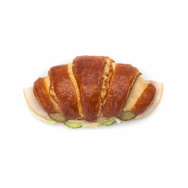 Draufsicht auf ein Croissant-Sandwich, gefüllt mit Wurst-, Käse- und Gurkenscheiben, auf weißem Hintergrund.