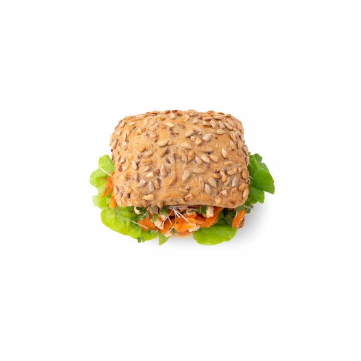 Ein quadratisches Sandwich mit einem entkernten Vollkornbrötchen, gefüllt mit grünem Blattsalat und geraspeltem Gemüse, fotografiert auf einem weißen Hintergrund.