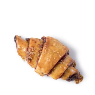 Ein einzelnes goldbraunes, halbmondförmiges Gebäck mit glänzender Oberfläche und bestreuten Zuckerkristallen, isoliert auf einem weißen Hintergrund.