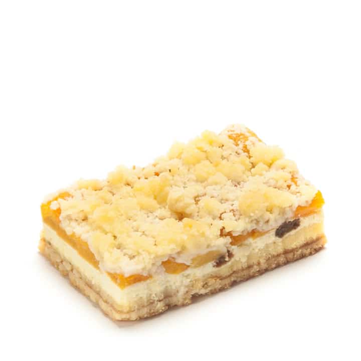 Ein rechteckiges Stück Streuselkuchen mit einer geschichteten Füllung, einschließlich gelber Fruchtstücke und Streusel, dargestellt auf weißem Hintergrund.