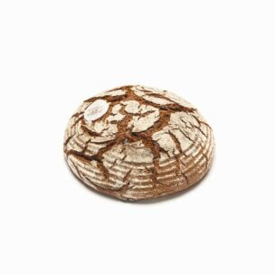 Ein runder Laib rustikales, handwerklich hergestelltes Brot mit einer rissigen, mehlbestäubten Kruste liegt auf einem schlichten weißen Hintergrund. Ein kleiner weißer Aufkleber ist in der Nähe des oberen linken Randes des Brotes angebracht.