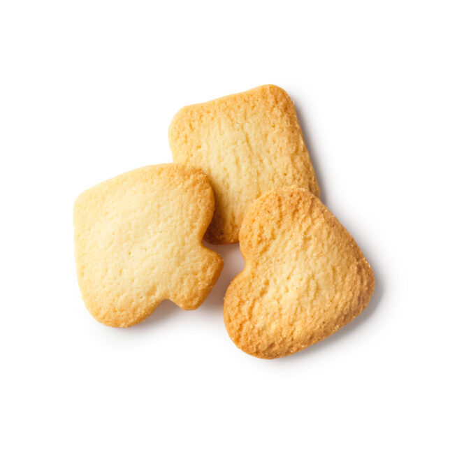 Drei goldbraune Kekse in verschiedenen Formen - ein Quadrat, ein Herz und ein Spaten - sind auf einem weißen Hintergrund angeordnet.