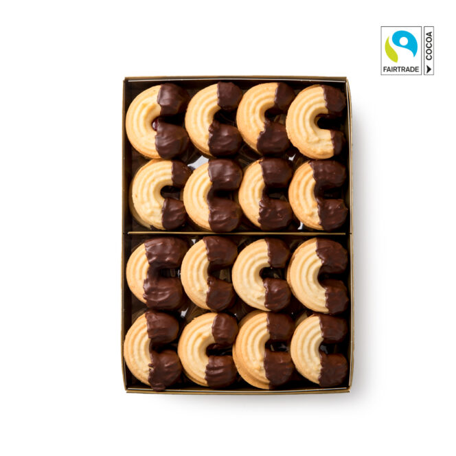 Eine Schachtel mit runden, geriffelten Butterkeksen, die zur Hälfte in Schokolade getaucht und ordentlich in Reihen angeordnet sind. Das Fairtrade-Kakao-Logo ist in der oberen rechten Ecke auf weißem Hintergrund zu sehen.