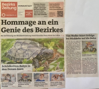 Titelseite einer deutschsprachigen Zeitung mit einem großen Schildkrötenschlupf, Schlagzeilen über lokale Nachrichten, einem Radfahrer und mehreren kleineren Bildern von Menschen. Hauptüberschrift: Hommage an ein Genie des Bezirkes.