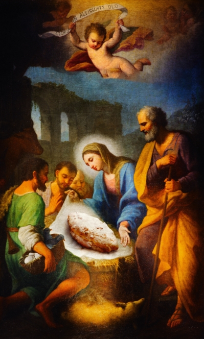 In einem Krippenbild mit Maria, Josef, Hirten und Engeln ersetzt ein großer Brotlaib das Jesuskind in der Krippe, was einen humorvollen und surrealen Effekt erzeugt.