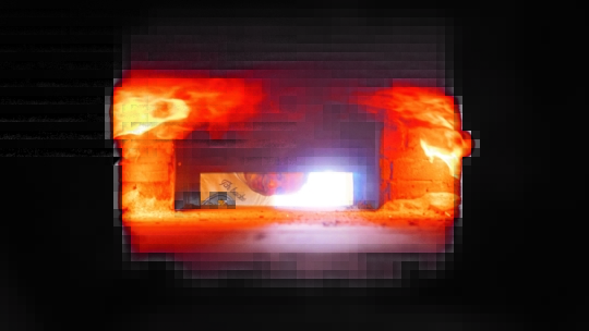 Blick in einen gemauerten Ofen mit leuchtend orangefarbenen Flammen an den Seiten. Durch die Öffnung des Ofens ist eine Person zu sehen, die mit einem Werkzeug hineingreift und von der starken Hitze angestrahlt wird.