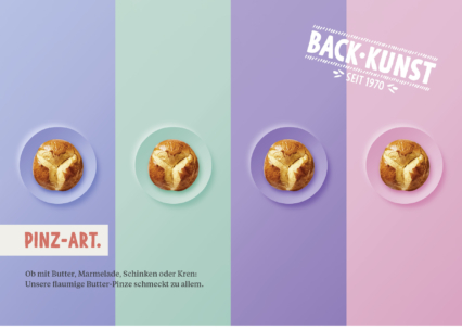 Drei gebutterte Brötchen stehen in der Mitte eines pastellblauen, lila und rosa Hintergrunds. Der Text lautet "Back-Kunst seit 1970" und "Pinz-Art" und bewirbt das Brot als lecker mit Butter, Marmelade, Schinken oder Meerrettich.