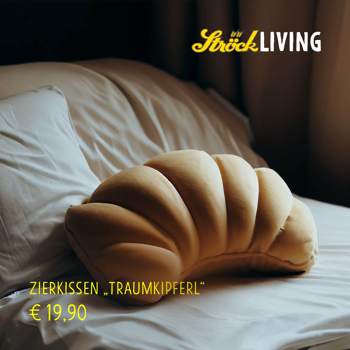 Ein Kissen in Form eines Hörnchens liegt auf einem sauber gemachten Bett mit weißer Bettwäsche; der Text lautet Ströck Living, Zierkissen Traumkipferl und €19,90.