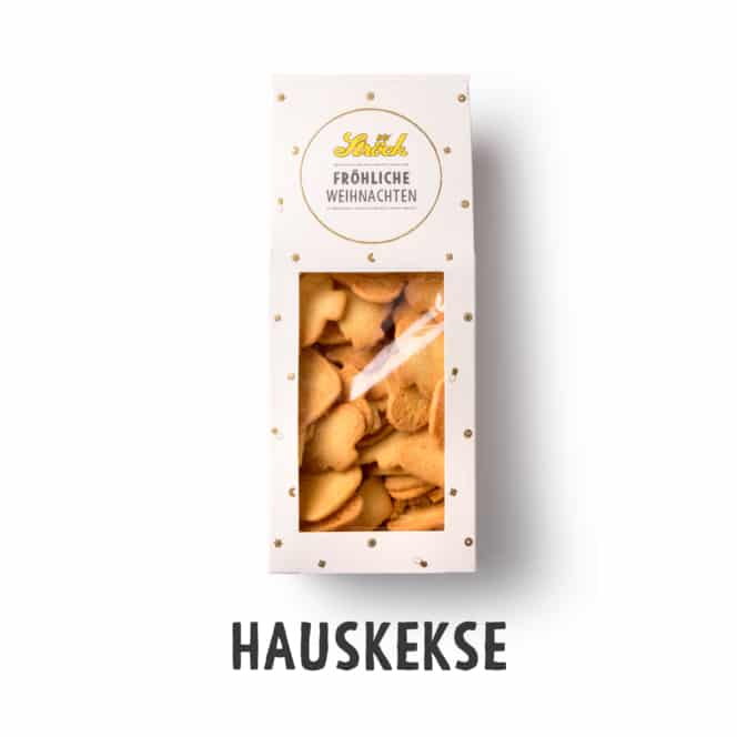 Eine weiße Schachtel mit der Aufschrift Fröhliche Weihnachten mit einem durchsichtigen Fenster, in dem sternförmige Kekse zu sehen sind. Unter der Schachtel steht das Wort Hauskekse.