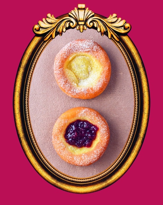 Zwei runde, mit Puderzucker bestäubte Gebäckstücke, das eine mit gelber Creme, das andere mit roter Marmelade gefüllt, in einem verzierten goldenen ovalen Rahmen auf violettem Hintergrund.