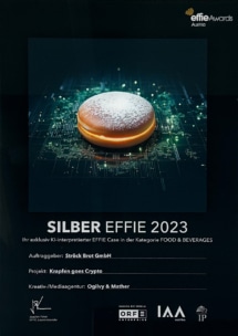 Ein Plakat für die Effie Awards Austria zeigt einen digital leuchtenden Krapfen. Es kündigt den SILBER EFFIE 2023 für das Projekt "Krapfen goes Crypto" der Ströck Brot GmbH an und zeigt Agentur-Credits und Award-Logos.
