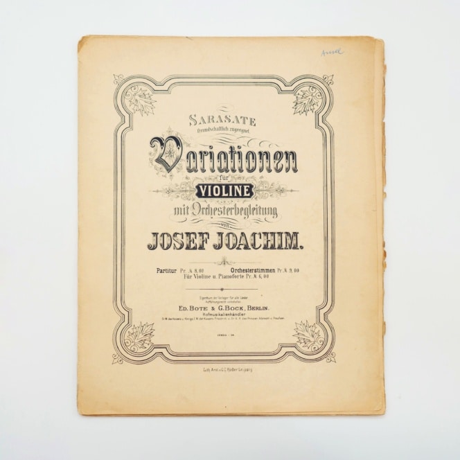 Ein alter Noteneinband mit dem Titel Variationen für die Violine mit Orchesterbegleitung von Josef Joachim, herausgegeben von Ed. Bote & G. Bock, Berlin, mit verschnörkelter, dekorativer Typographie auf gealtertem Papier.
