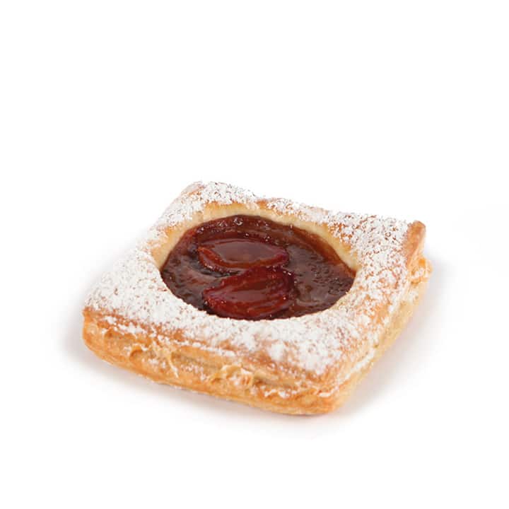 Ein mit Puderzucker bestreutes quadratisches Gebäck, gefüllt mit roter Fruchtmarmelade und geschnittenen Früchten, auf weißem Grund.