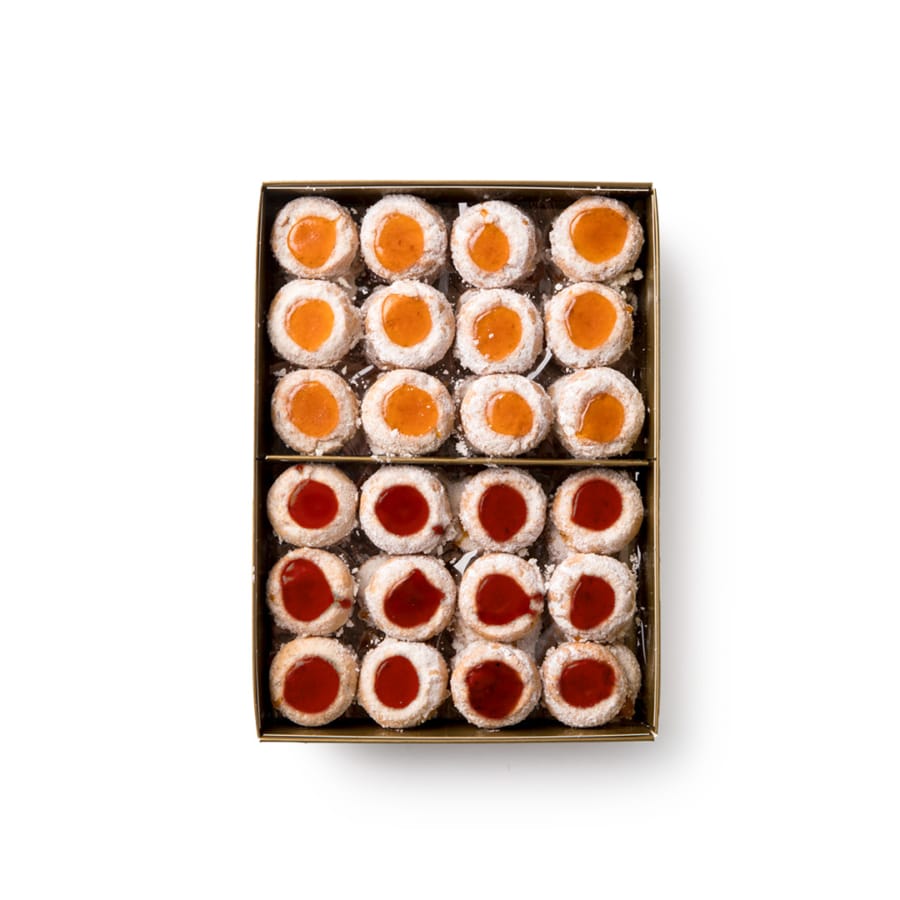 Eine Schachtel mit runden, mit Puderzucker bestreuten Keksen, die in Reihen angeordnet und in der Mitte mit Orangen- und roter Fruchtmarmelade gefüllt sind, unterteilt in zwei Teile.