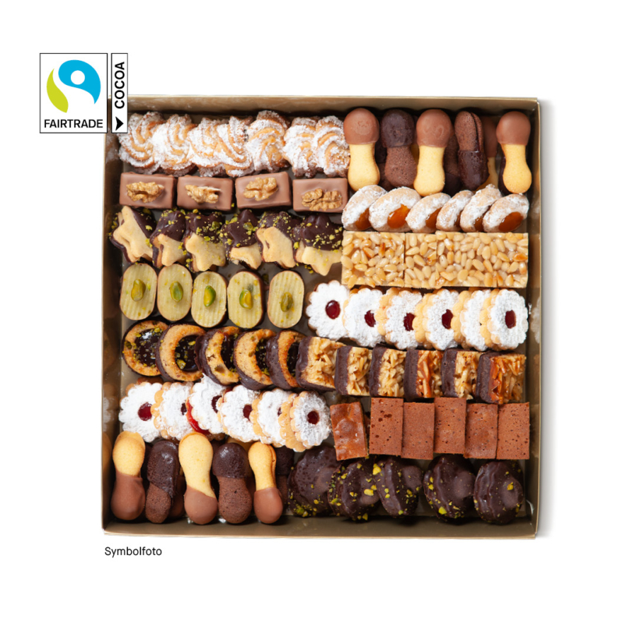 Eine Schachtel, gefüllt mit einer Vielzahl von fein säuberlich sortierten Keksen, darunter in Schokolade getauchte, mit Nüssen belegte und mit Puderzucker überzogene Kekse. Das Fairtrade-Kakao-Logo erscheint in der oberen linken Ecke.
