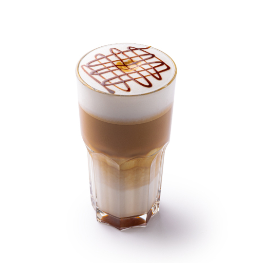 Ein Glas Milchkaffee mit Milchschaum und Schokoladensirup in einem Kreuzmuster vor weißem Hintergrund.
