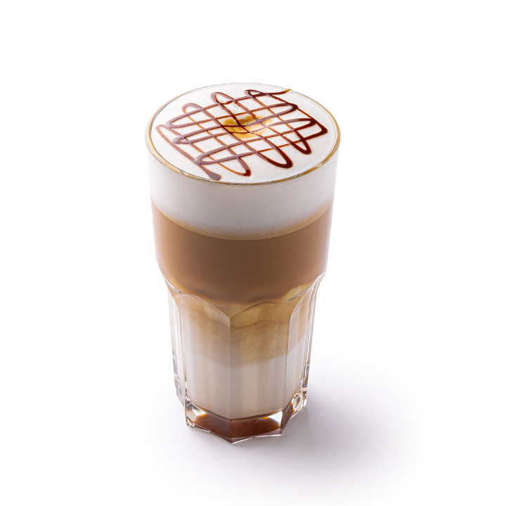 Ein Glas Milchkaffee mit Milchschaum und Schokoladensirup in einem Kreuzmuster vor weißem Hintergrund.