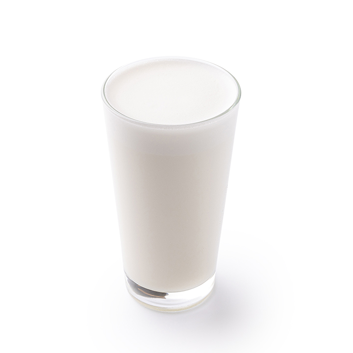Ein klares, mit Milch gefülltes Glas auf weißem Hintergrund.