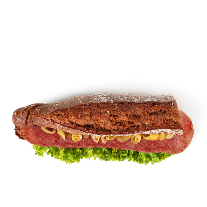 Ein Sandwich aus dunklem Brot, gefüllt mit Salat, Salamischeiben und Senf, von oben gesehen auf einem weißen Hintergrund.