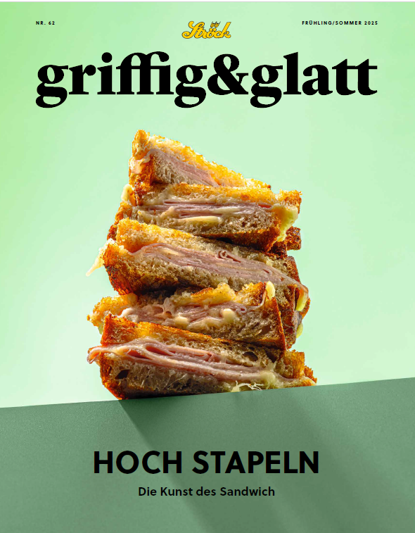 Ein Stapel gegrillter Sandwiches, gefüllt mit geschmolzenem Käse und Fleisch, ist auf der Titelseite einer Zeitschrift mit dem Titel griffig & glatt abgebildet. Die Überschrift lautet HOCH STAPELN Die Kunst des Sandwichs.