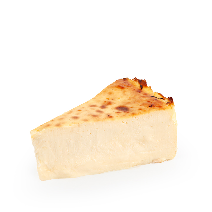 Ein einzelnes Stück Käsekuchen mit einer goldbraunen, leicht karamellisierten Oberfläche, dargestellt vor einem schlichten weißen Hintergrund.
