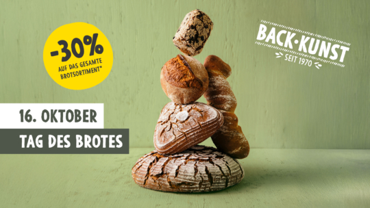 Ein Stapel verschiedener handwerklich hergestellter Brote wird auf einer Holzfläche balanciert. Ein gelber Kreis wirbt für 30% auf das gesamte Brotsortiment. Der Text lautet 16. Oktober Tag des Brotes und Back-Kunst seit 1970 auf grünem Hintergrund.