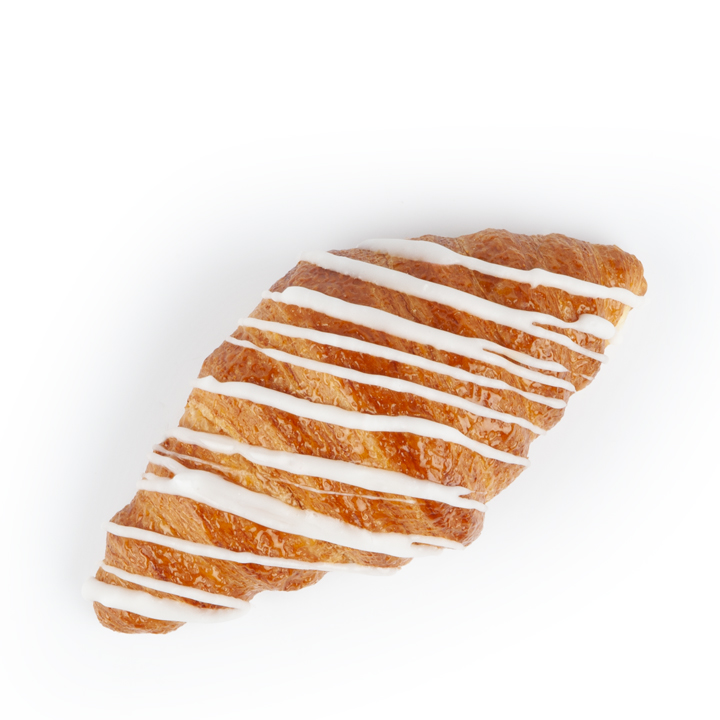 Ein goldbraunes Croissant ist mit diagonalen weißen Zuckergussstreifen auf weißem Hintergrund belegt.