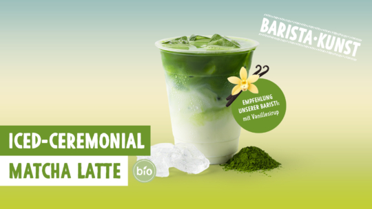 Ein klarer Becher mit einem eisgekühlten zeremoniellen Matcha Latte aus unserer Bäckerei, oben mit grünem Matcha, darunter Milch, Eiswürfel, Matcha-Pulver und daneben eine Vanilleblüte. Der Text hebt die Begriffe „Eisgekühlter zeremonieller Matcha Latte“, „Bio“ und „Barista-Kunst“ hervor.